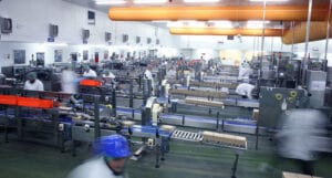 Busy Factory With Automated Machinery And Workers.